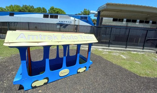 Child-size auto train car in Sanford station play area, with real auto train in background