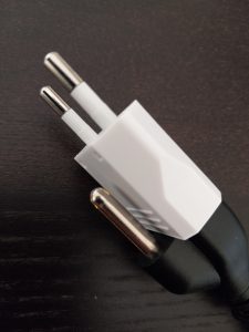 Laptop plug inserted into adapter for use in a Portuguese wall outlet.